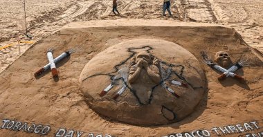 Children play near a sand sculpture that was made to create awareness against the tobacco use on "World No Tobacco" day at Elliot’s beach in Chennai, India, May 31, 2022. (AFP Photo)