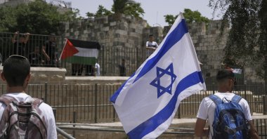 Palestinians and Israelis wave their national flags outside occupied East Jerusalem's Old City as Israelis mark Jerusalem Day, an Israeli holiday celebrating the capture of the Old City during the 1967 Mideast war, Palestine, May 29, 2022. (AP Photo)