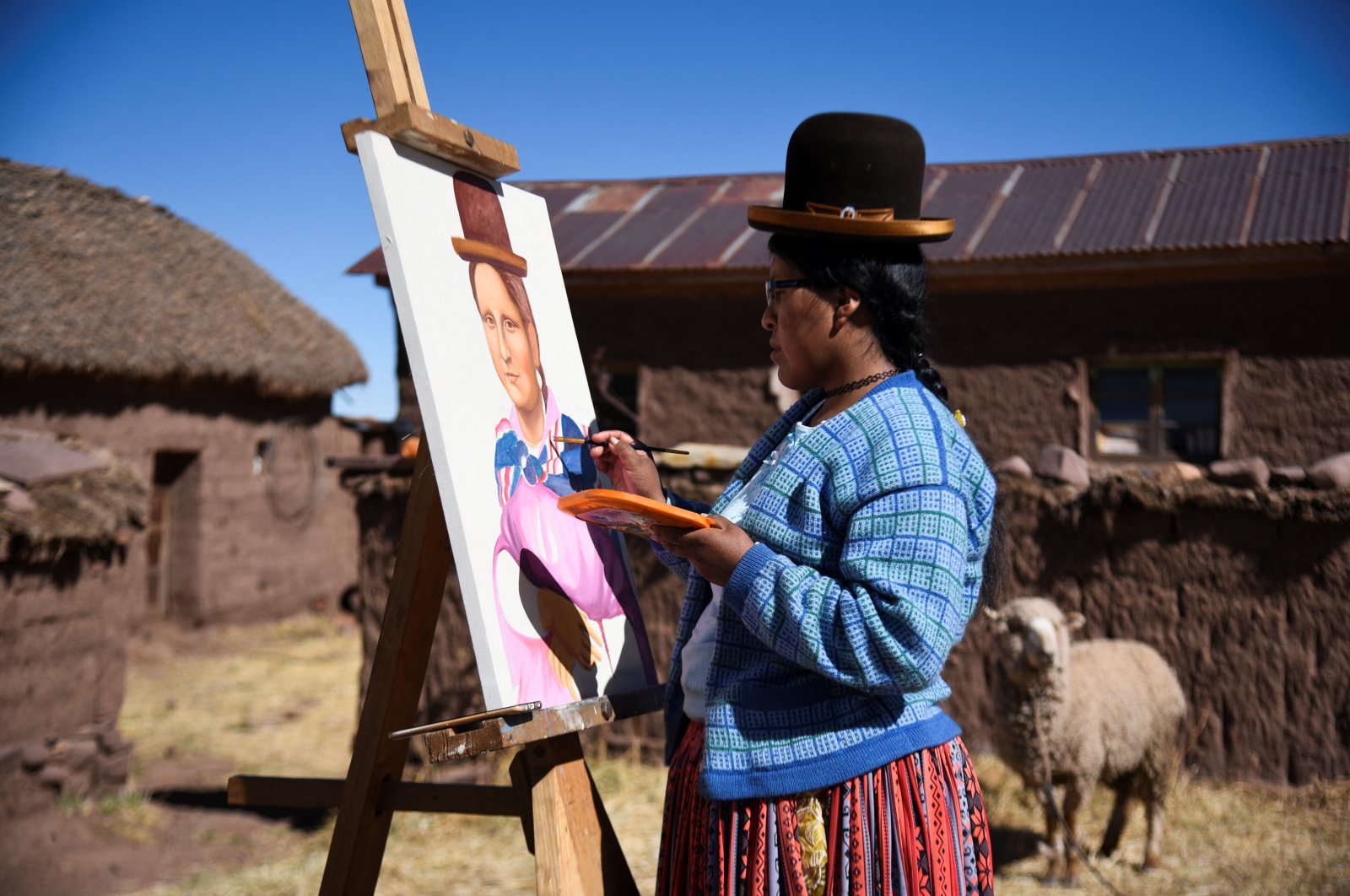 Claudia Callizaya, 32, a Bolivian painter known as Claudina, applies final touches to her work, cholita-style Mona Lisa painting, at her house in Kalla Baja, Bolivia, May 29, 2022. (Reuters Photo)