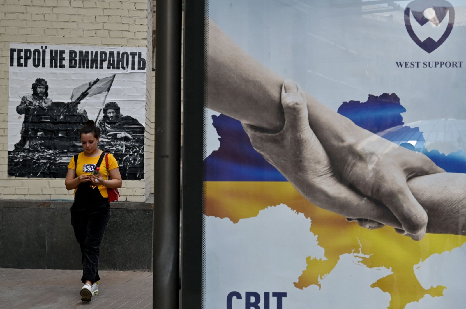 A girl walks past placards reading &quot;Heroes don&#039;t die&quot; (L) and &quot;The world with Ukraine&quot; in the center of Kyiv, Ukraine, June 1, 2022. (AFP Photo)