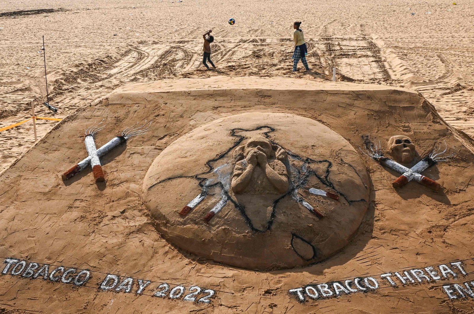 Children play near a sand sculpture that was made to create awareness against the tobacco use on "World No Tobacco" day at Elliot’s beach in Chennai, India, May 31, 2022. (AFP Photo)
