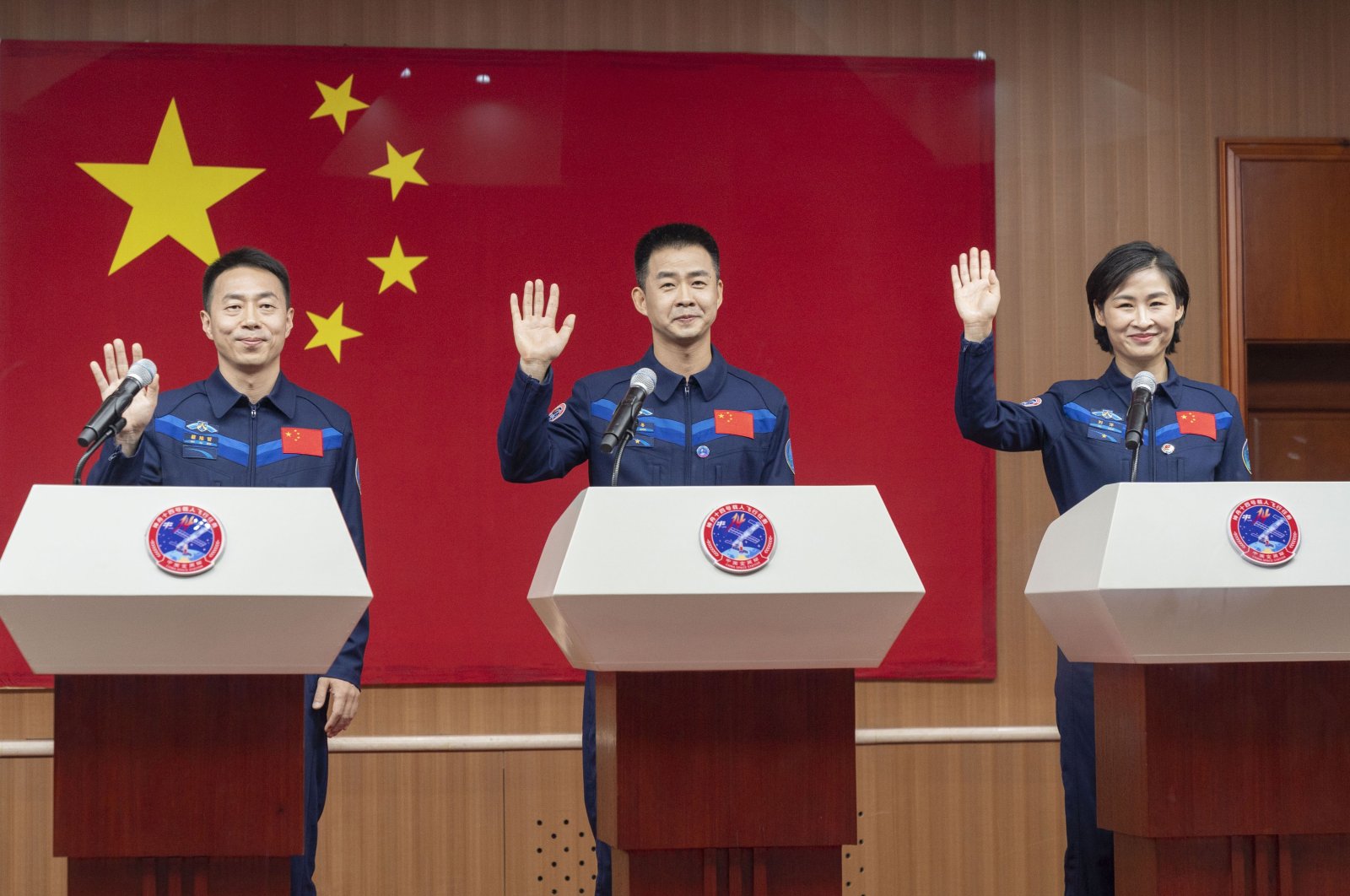 Photo released by Xinhua News Agency, shows Chinese astronauts (L-R) Cai Xuzhe, Chen Dong and Liu Yang, waving as they attend a press conference for the upcoming Shenzhou-14 mission at the Jiuquan Satellite Launch Center, Beijing, China, June 4, 2022. (AP Photo)