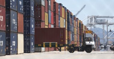 A truck drives by stacks of shipping containers at the Port of Oakland in Oakland, California, U.S., May 20, 2022. (AFP Photo)