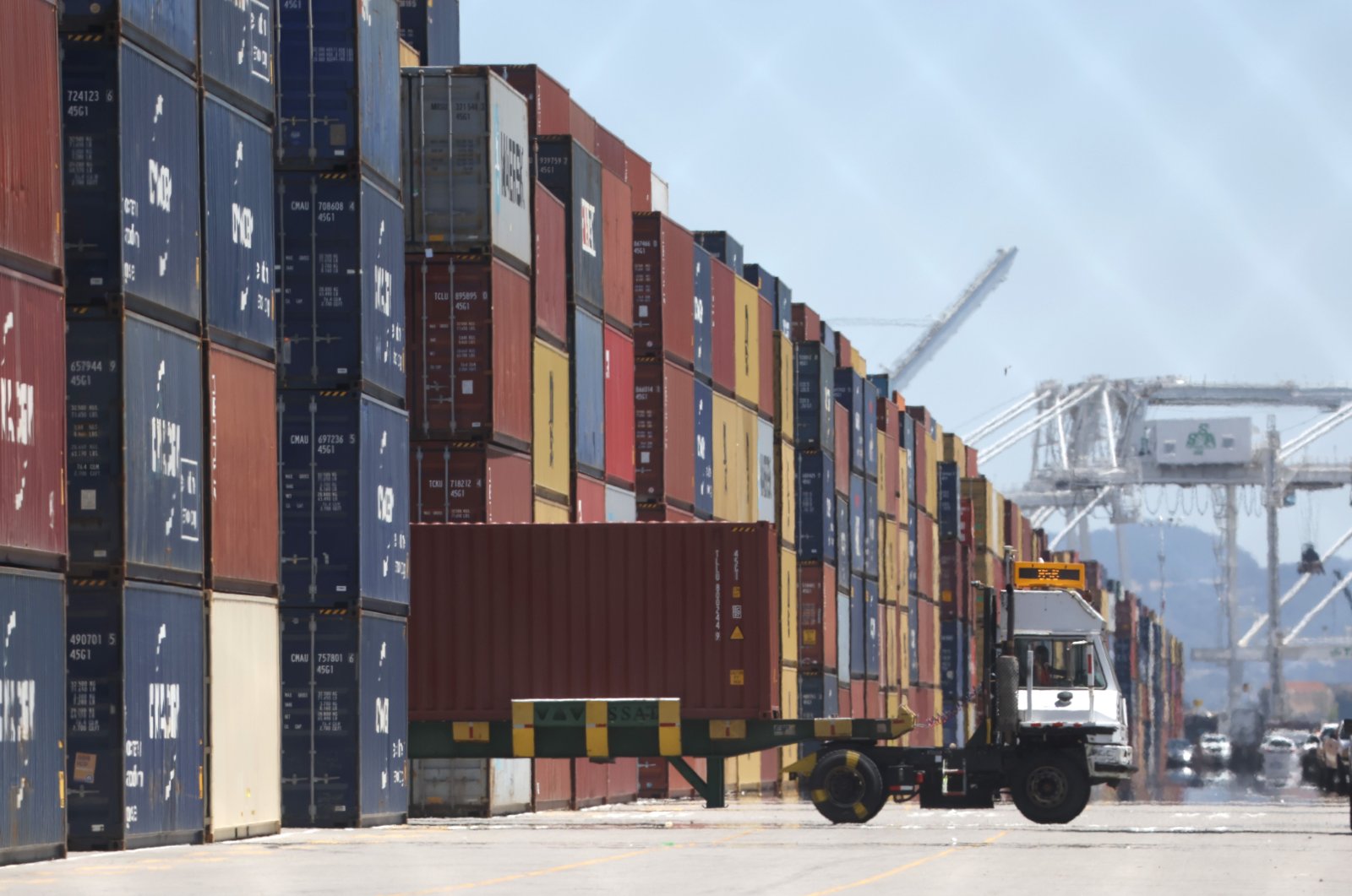 A truck drives by stacks of shipping containers at the Port of Oakland in Oakland, California, U.S., May 20, 2022. (AFP Photo)