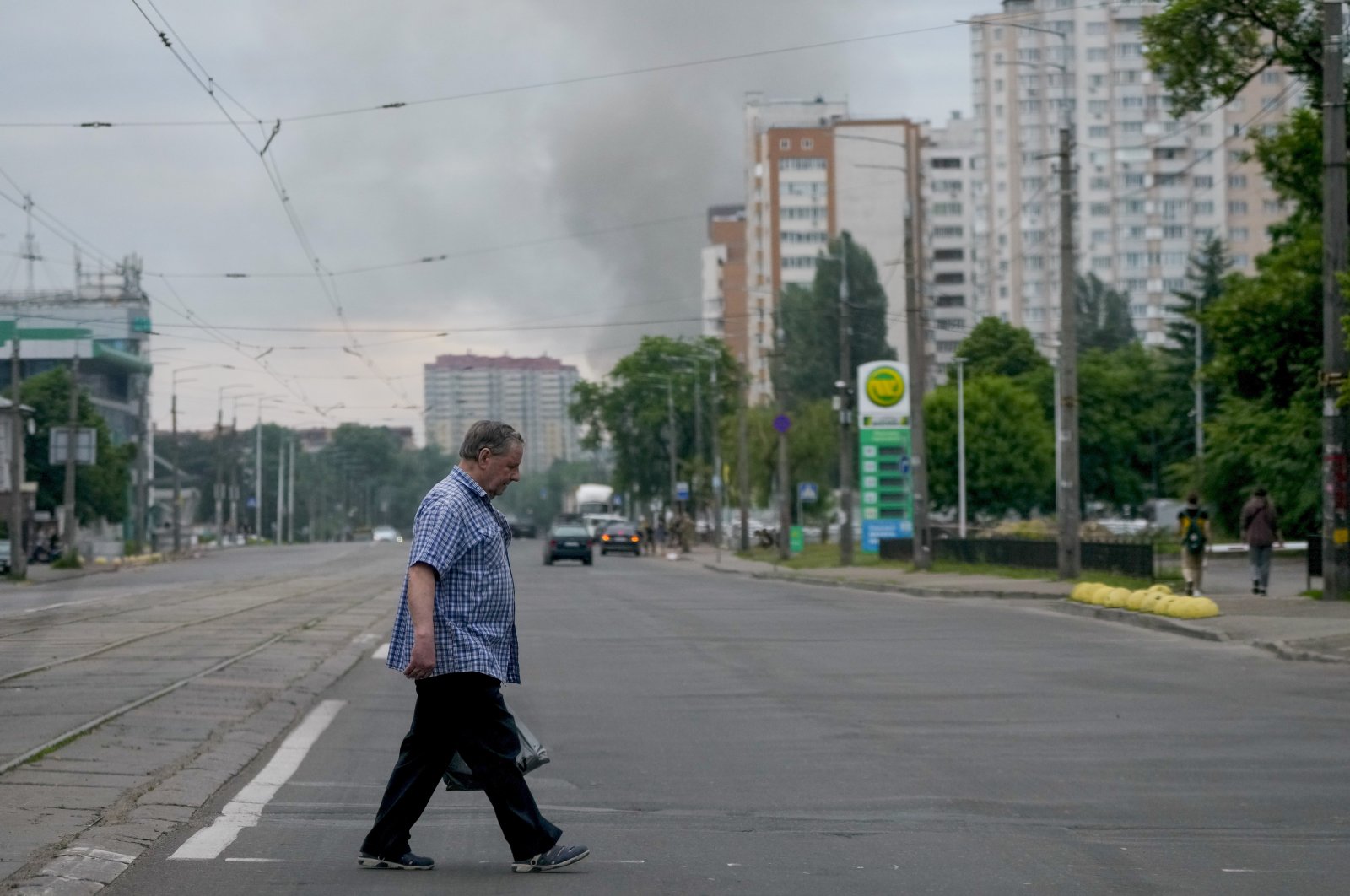 A man crosses a street as smoke rises in the background after Russian missile strikes in Kyiv, Ukraine, June 5, 2022. (AP Photo)