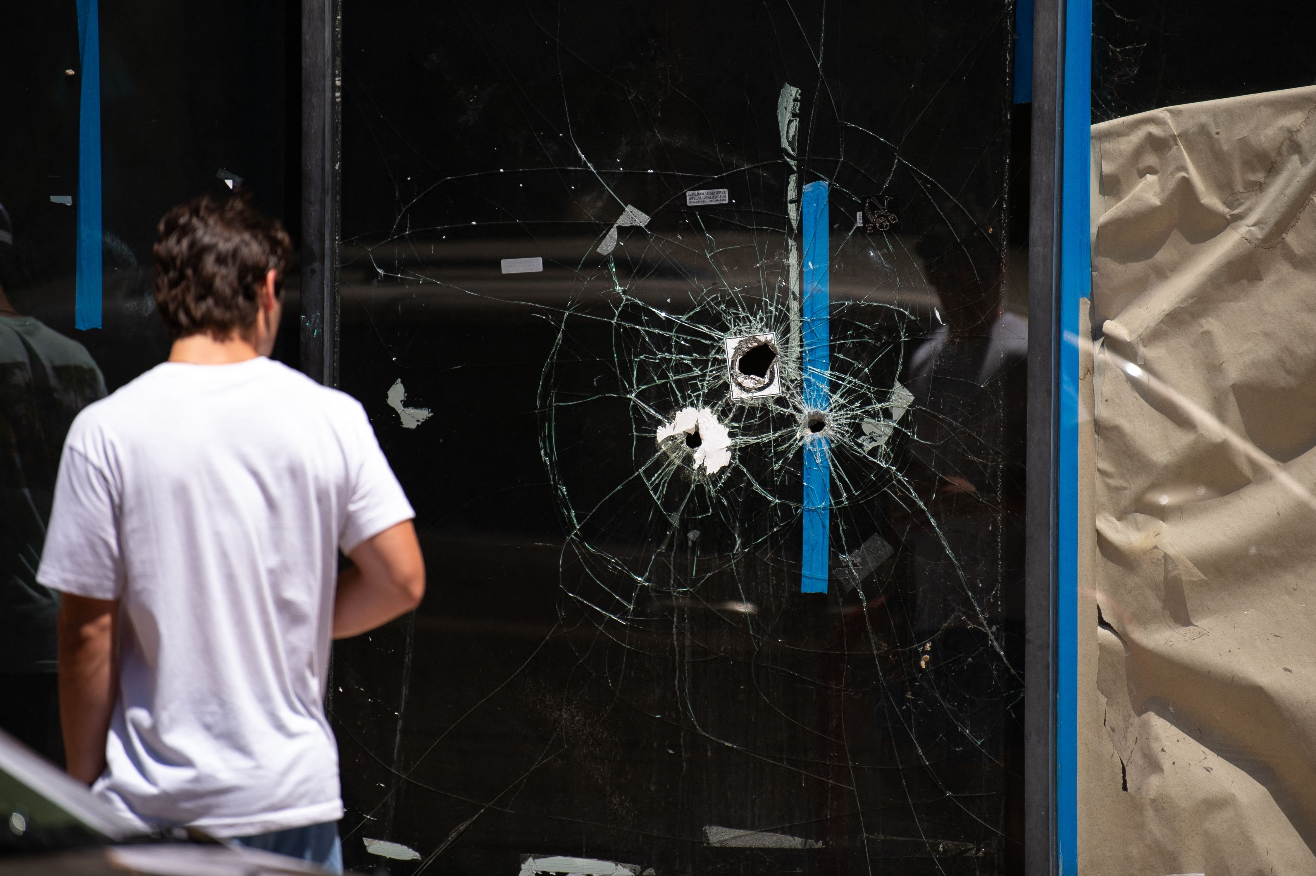A pedestrian walks past bullet holes in the window of a storefront on South Street in Philadelphia, Pennsylvania, June 5, 2022. (Photo by Kriston Jae Bethel / AFP)