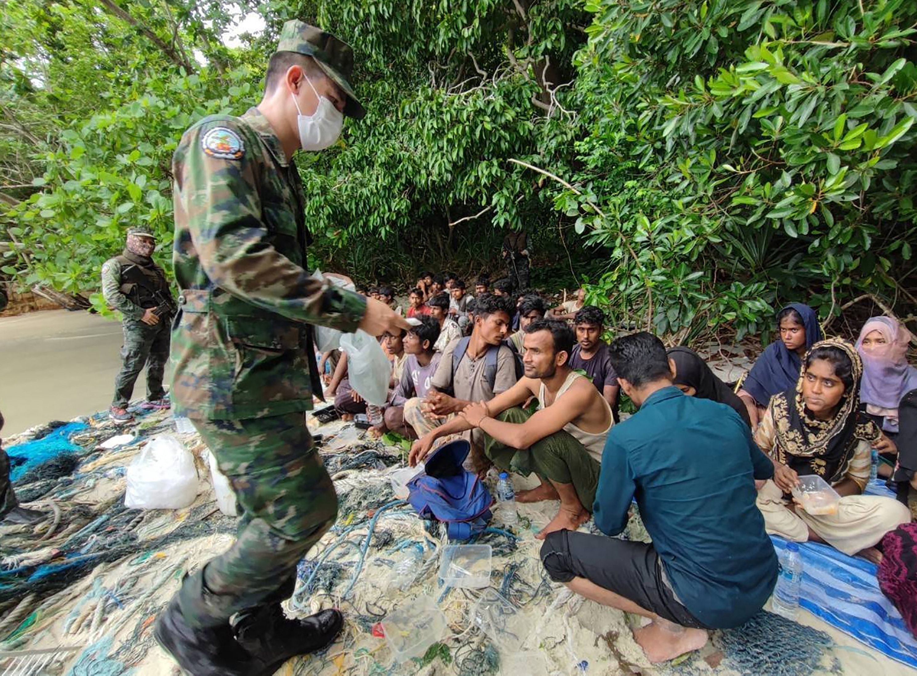 This handout from the Royal Thai Navy taken on June 4, 2022, and released on June 5 shows members of the Thai Navy and park officials offering food to Rohingyas found stranded on the Thai island of Koh Dong. (AFP Photo)