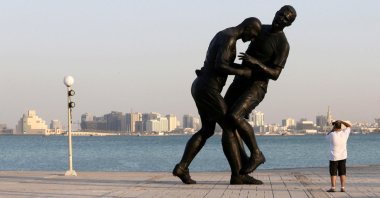 A man photographs a bronze sculpture titled "Coup de Tete" by Algerian-born French artist Adel Abdessemed during its installation, Doha, Qatar, Oct. 7, 2013. (Reuters Photo)