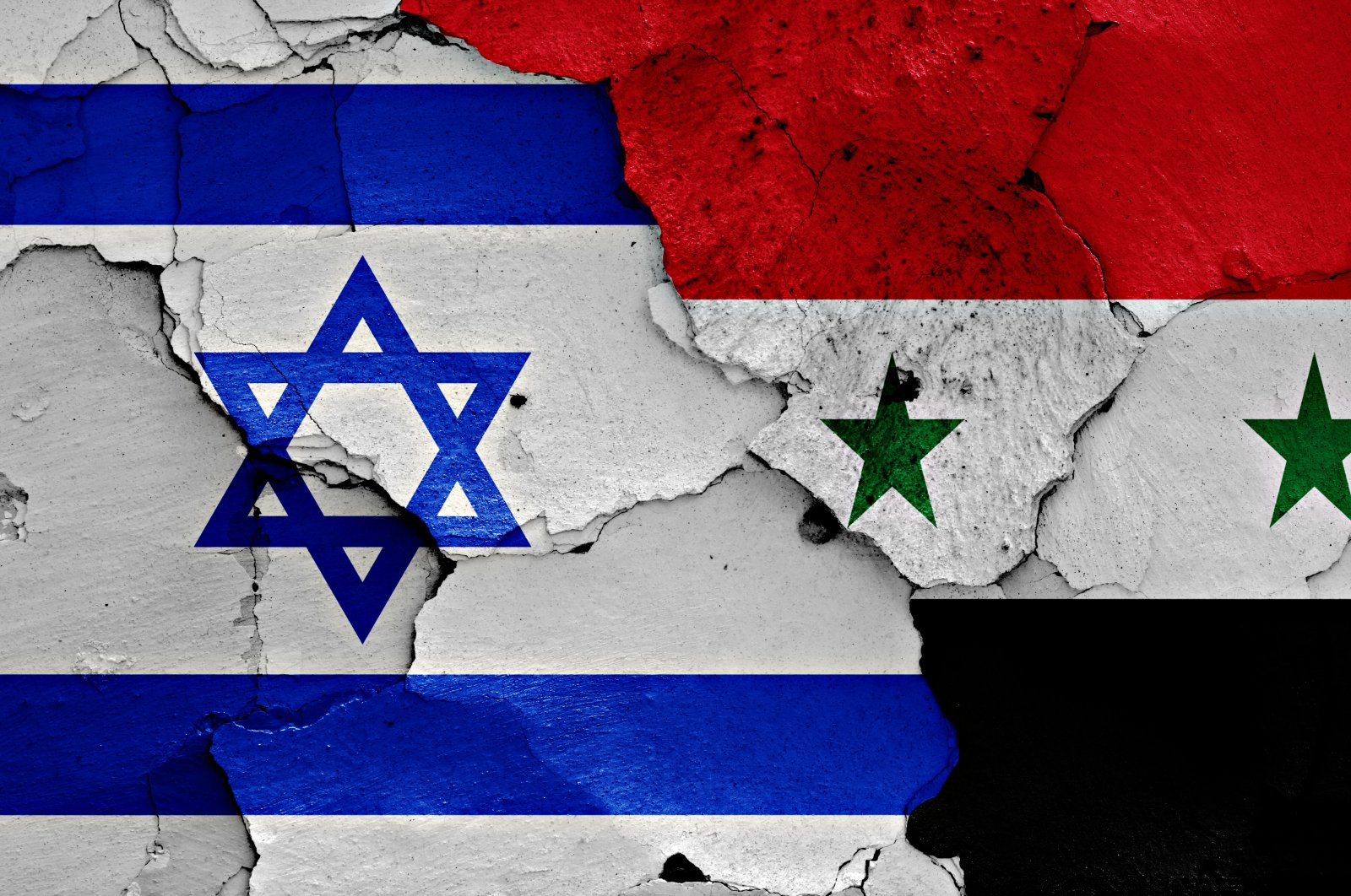 The flags of Israel and Syria are seen on a cracked wall. (ShutterStock Photo)