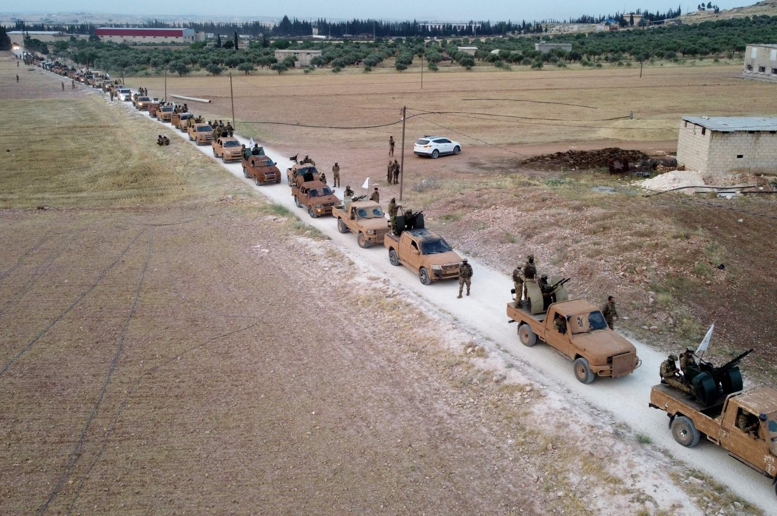 This aerial view shows Turkey-backed Syrian fighters as they arrive to take part in a military exercise in the countryside of the northern city of Manbij, on June 2, 2022. (AFP)