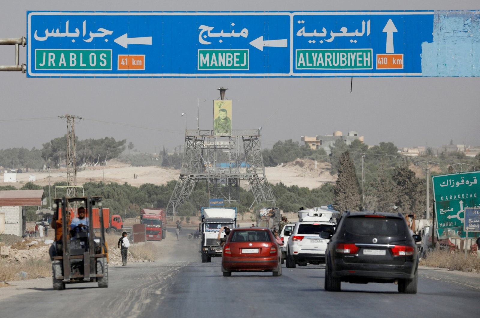 Cars pass under a road sign that shows the direction to Manbij city, at the entrance of Manbij, Syria October 15, 2019. REUTERS/Omar Sanadiki/File Photo