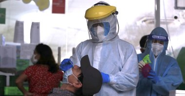 A health worker takes a sample from a man for a COVID-19 test in Hanoi, Vietnam, Jan. 6, 2022. (AP Photo)