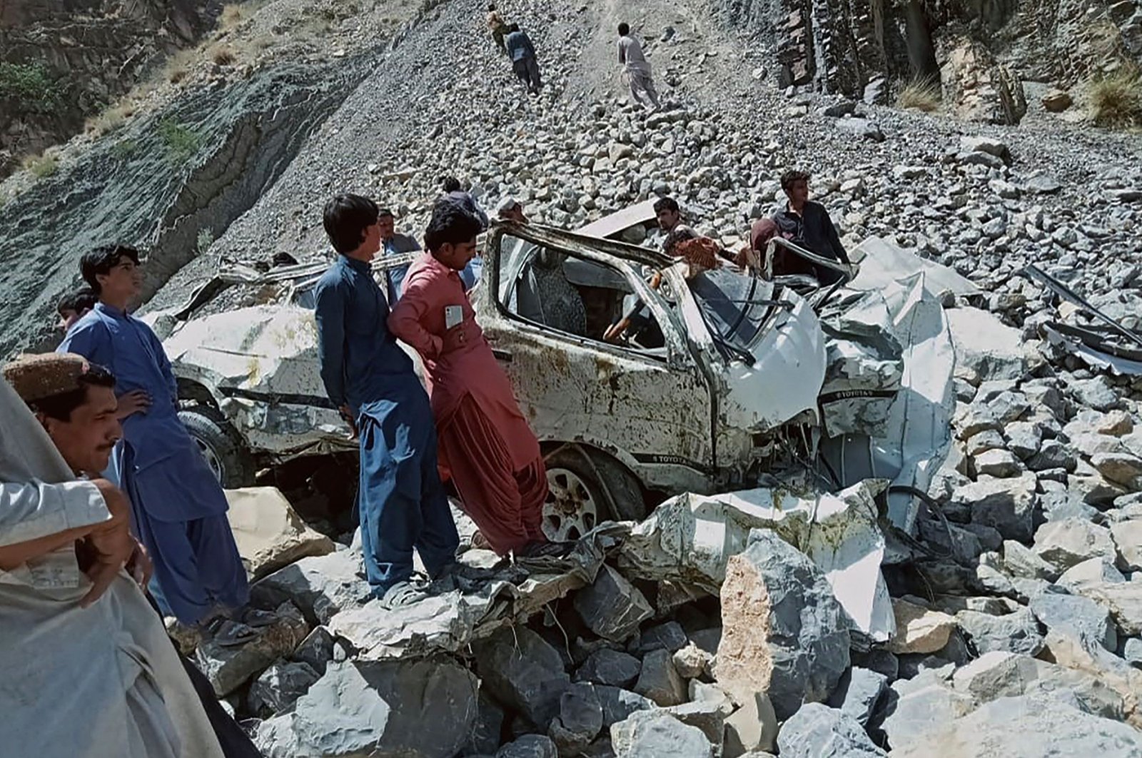 Onlookers gather around the wreckage of a passenger van that plunged into a deep ravine in Qila Saifullah district of Balochistan province, Pakistan, June 8, 2022. (AFP Photo)