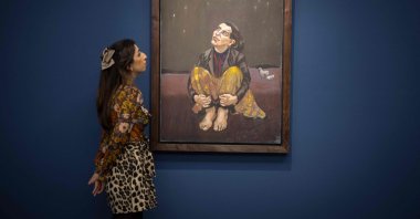 A gallery assistant poses with an artwork entitled Good Dog by Portuguese-British artist Paula Rego during a photocall at Sotheby's auction house in central London, England, Oct. 8, 2021. (AFP Photo)