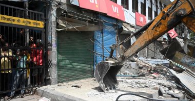 Residents watch as a bulldozer demolishes an illegal structure in a residential area during an anti-encroachment drive following clashes between members of two communities in Jahangirpuri, New Delhi, India, April 20, 2022. (AFP Photo)