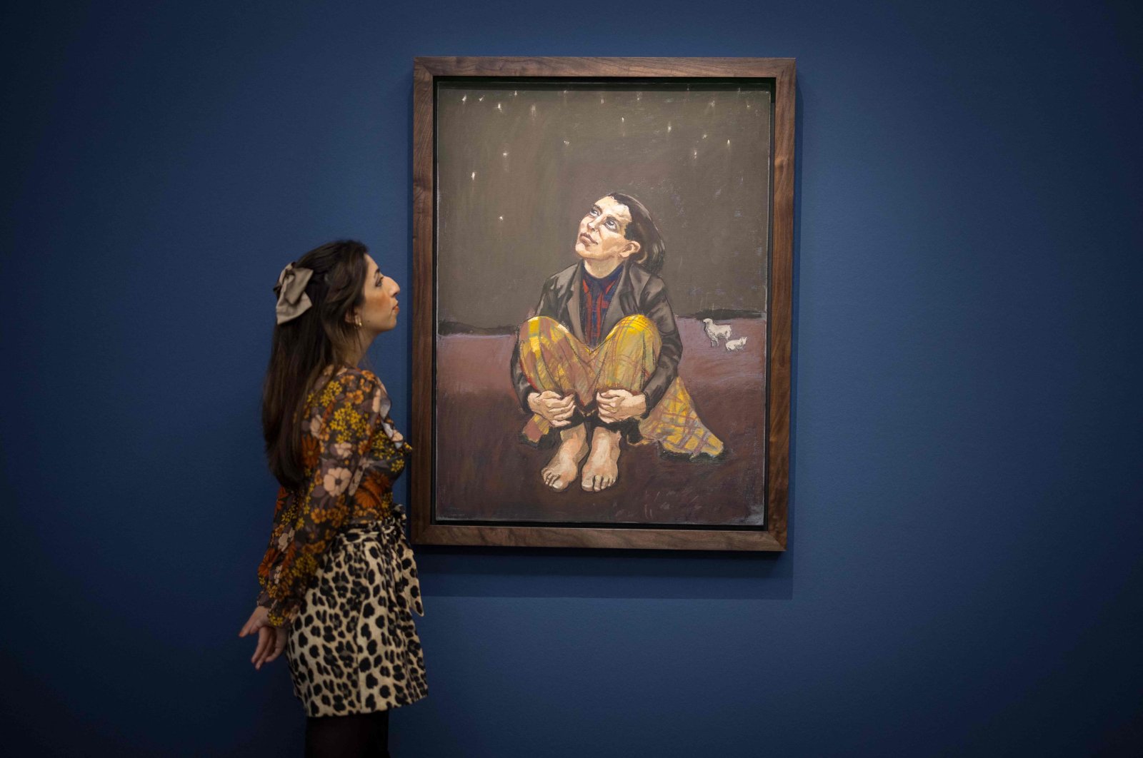 A gallery assistant poses with an artwork entitled Good Dog by Portuguese-British artist Paula Rego during a photocall at Sotheby&#039;s auction house in central London, England, Oct. 8, 2021. (AFP Photo)