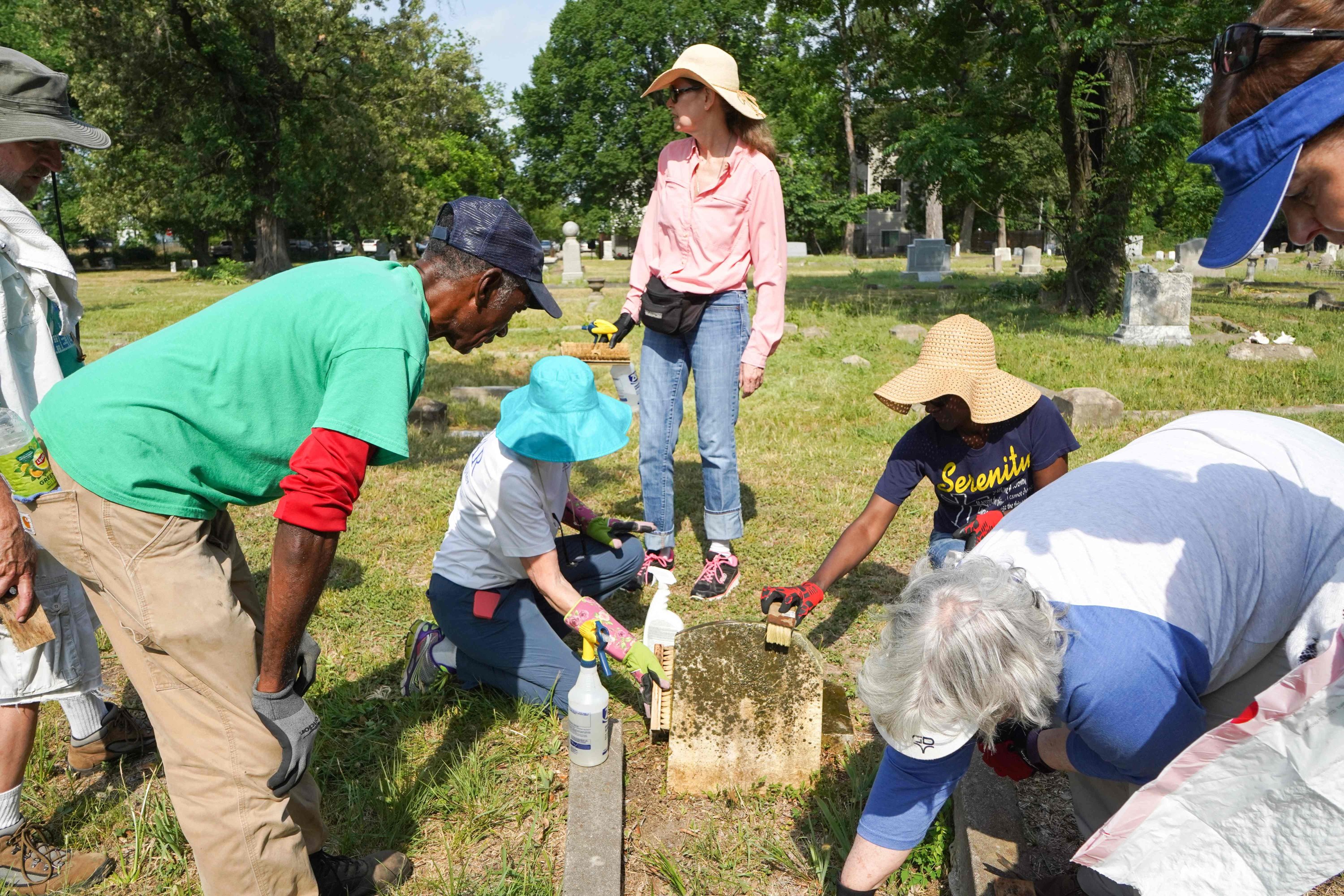 Charles Cook dikelilingi oleh para sukarelawan yang datang untuk menjaga kebersihan nisan kuburan pada Hari Aksi di Pemakaman Olivewood di Houston, Texas, AS, 21 Mei 2022. (AFP Photo)