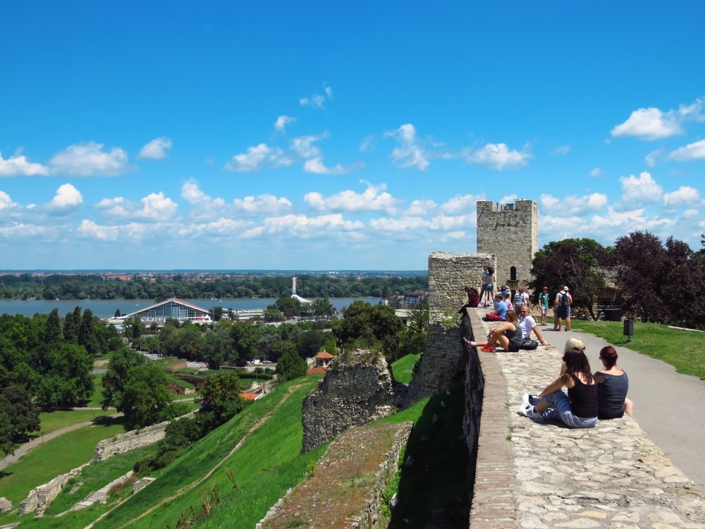 Foreign tourists resting on the wall and enjoying the view from the Kalemegdan fortress, Belgrade, Serbia, July 20, 2018. (Shutterstock Photo)