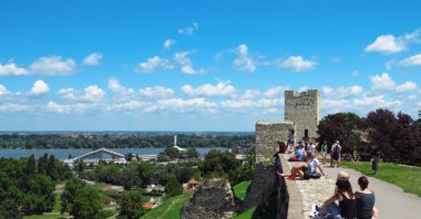 Foreign tourists resting on the wall and enjoying the view from the Kalemegdan fortress, Belgrade, Serbia, July 20, 2018. (Shutterstock Photo)