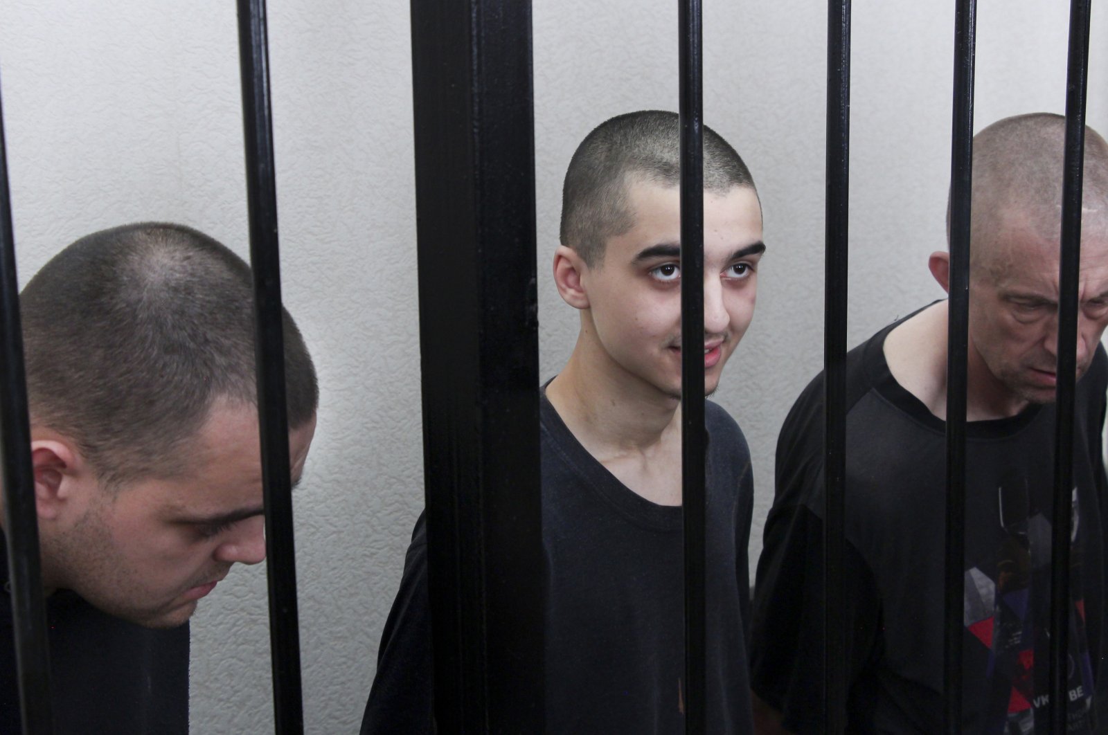 Two British citizens Aiden Aslin (L), Shaun Pinner (R), and Moroccan Saaudun Brahim (C) sit behind bars in a courtroom in Donetsk, in the territory which is under the Government of the Donetsk People&#039;s Republic control, eastern Ukraine, June 9, 2022. (AP Photo)