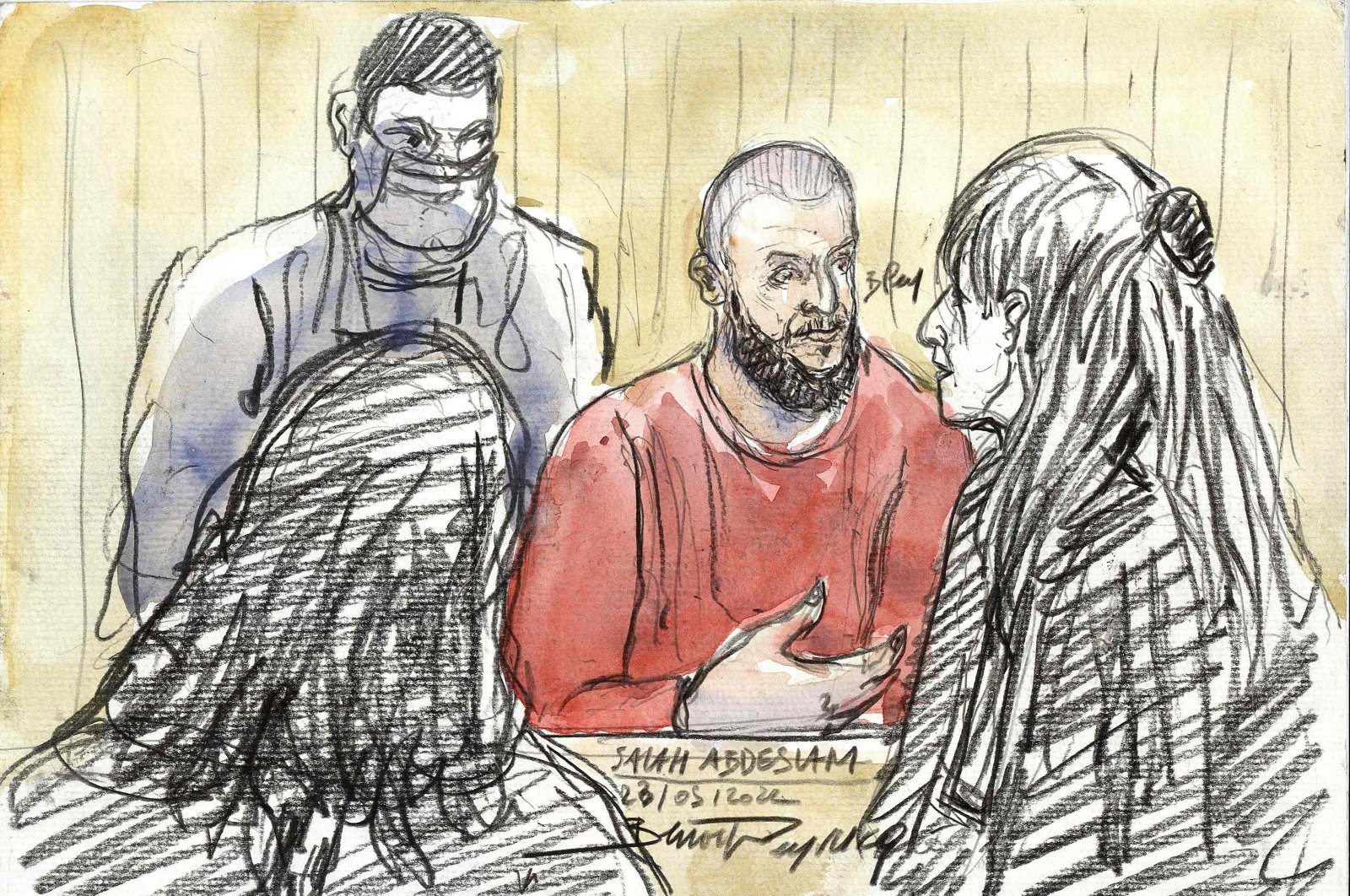 A sketch depicting defendant Salah Abdeslam (C), the prime suspect, standing in front of French lawyer Claire Josserand Schmidt (R) during the trial of the November 2015 terrorist attacks that saw 130 people killed, Palais de Justice courthouse, Paris, France, May 23, 2022. (AFP File Image)