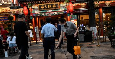 An employee sprays disinfectant outside a restaurant along a street in Beijing, China, June 6, 2022. (AFP Photo)