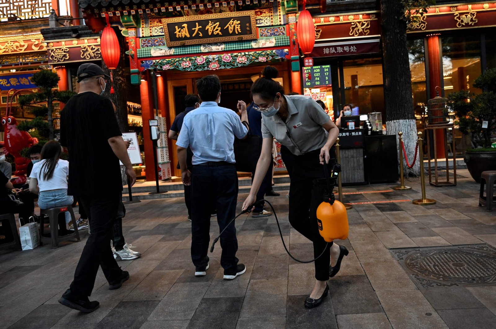 An employee sprays disinfectant outside a restaurant along a street in Beijing, China, June 6, 2022. (AFP Photo)