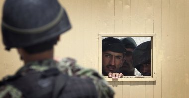Afghan soldiers look out through the security hole of one of the gates at the airport after a firing incident in Kabul, Afghanistan, April 27, 2011. (AP File Photo)