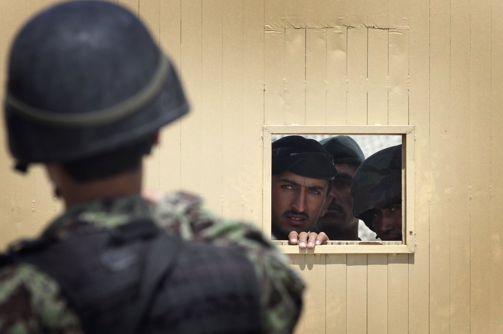 Afghan soldiers look out through the security hole of one of the gates at the airport after a firing incident in Kabul, Afghanistan, April 27, 2011. (AP File Photo)