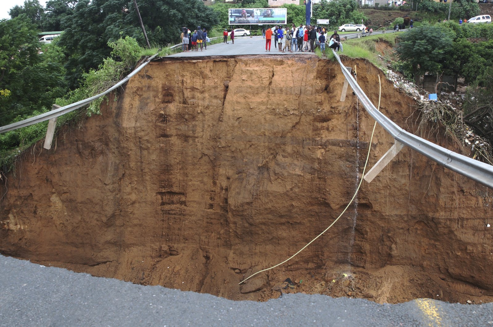 Stranded people stand in front of a bridge that was swept away in Ntuzuma, outside Durban, South Africa, April 12, 2022. (AP Photo)