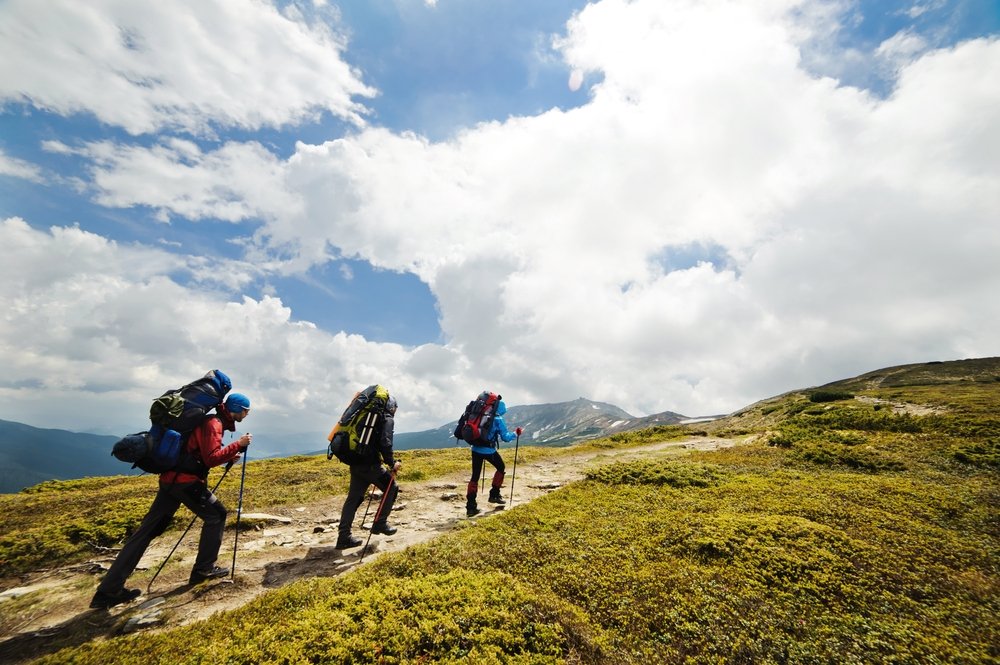 A group of people with backpacks walking along a mountain path. (Shutterstock Photo)