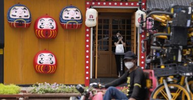 A restaurant worker waits at the entrance for customers, June 13, 2022, in Beijing. (AP Photo)