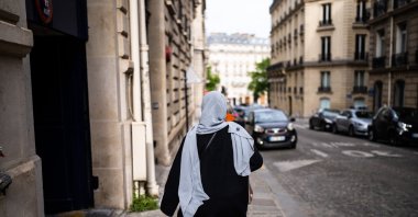 A Muslim woman wearing a headscarf walks with her back to the camera on the sidewalk in Paris, France, April 28, 2022. (Reuters File Photo)