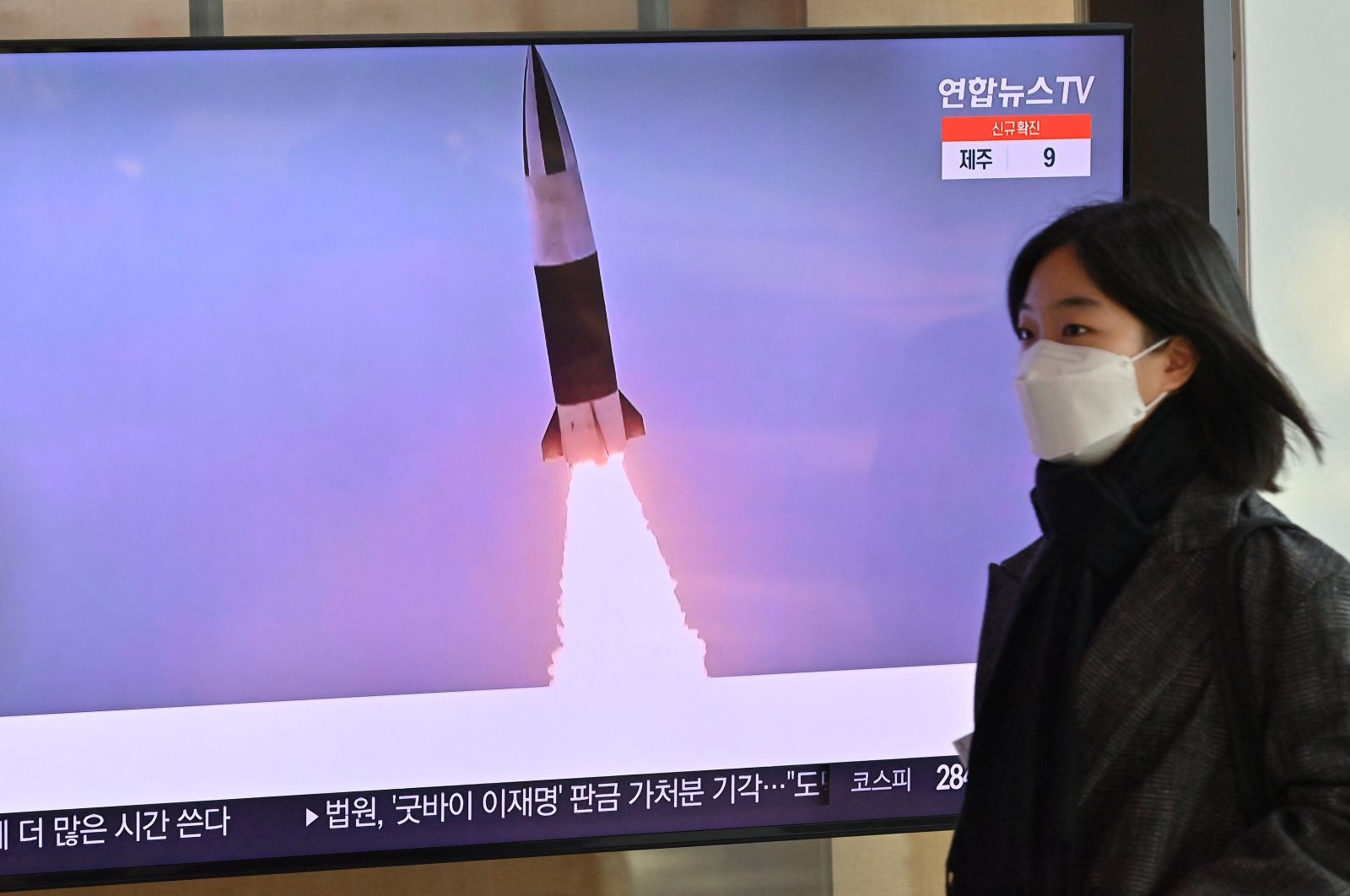 A woman walks past a television screen showing a news broadcast with file footage of a North Korean missile test, Seoul, South Korea, Jan. 20, 2022. (AFP Photo)