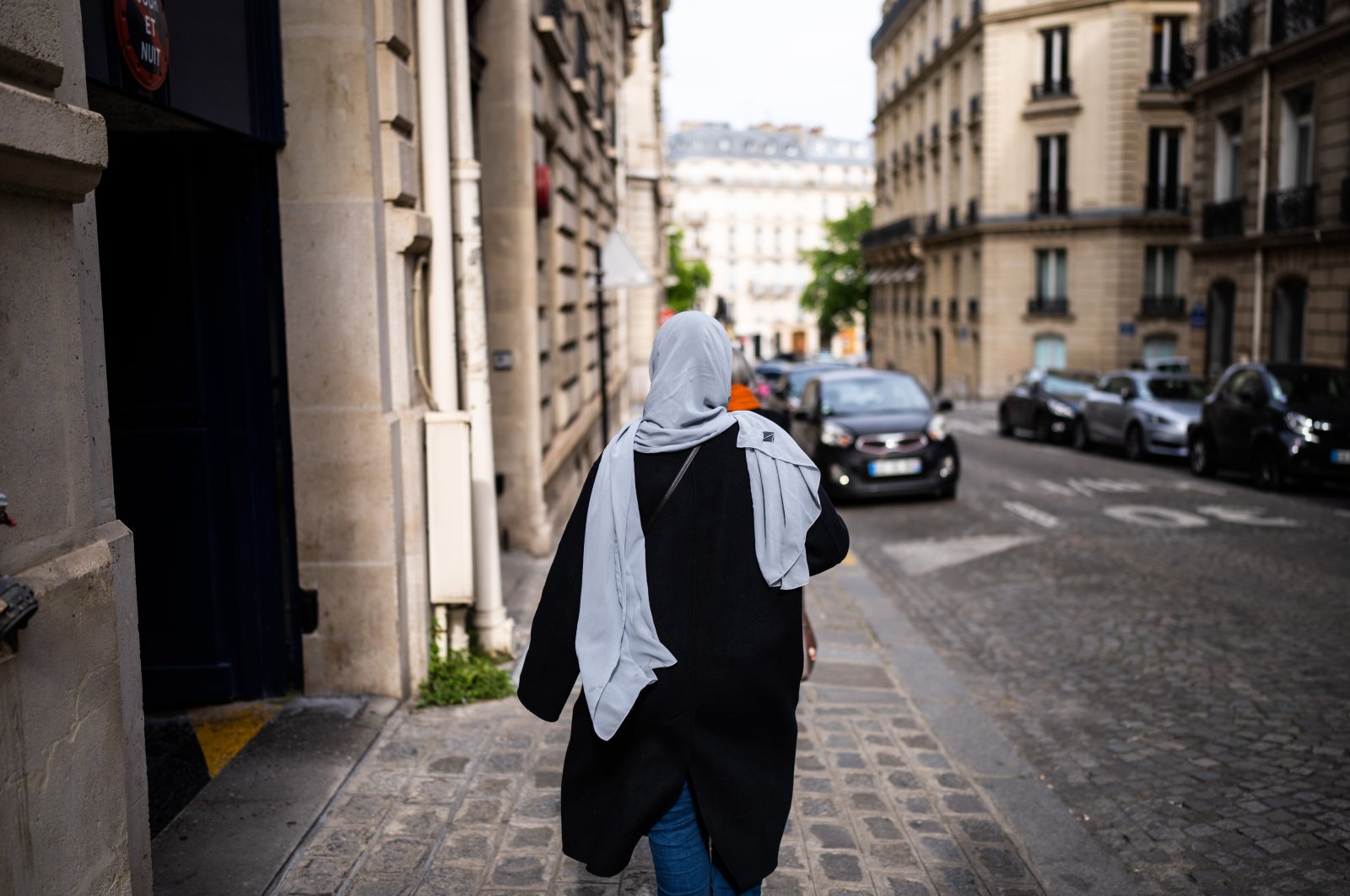 A Muslim woman wearing a headscarf walks with her back to the camera on the sidewalk in Paris, France, April 28, 2022. (Reuters File Photo)