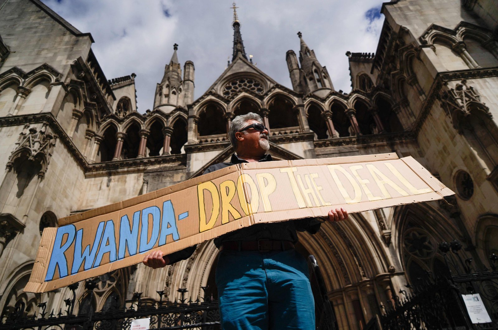 A demonstrator holds a placard during a protest against Britain&#039;s Rwanda asylum plan outside the High Court in London, U.K., June 13, 2022. (AFP Photo)