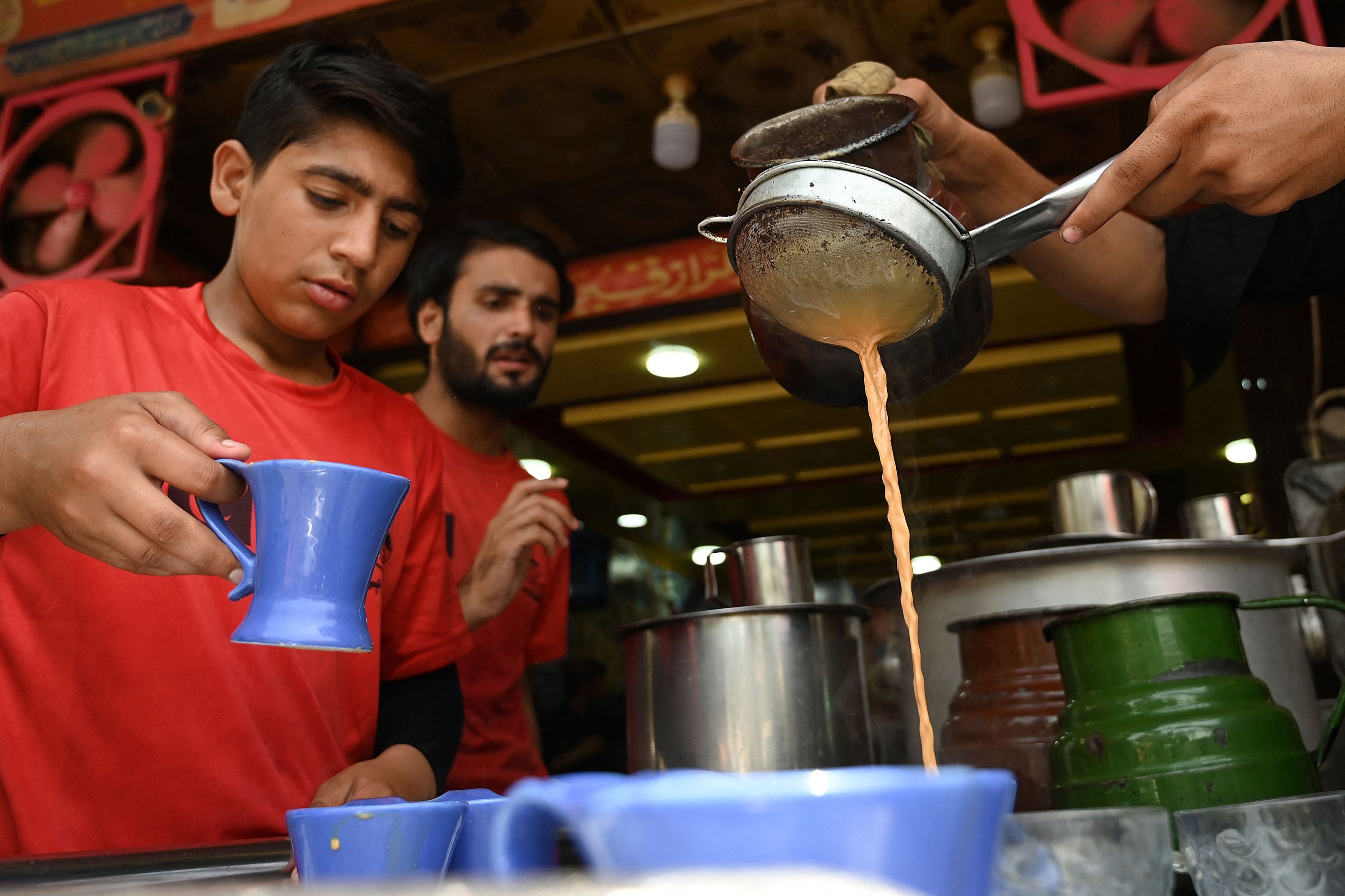 Para pelayan bersiap untuk menyajikan teh kepada pelanggan di sebuah restoran di Islamabad, Pakistan, 15 Juni 2022. (AFP Photo)