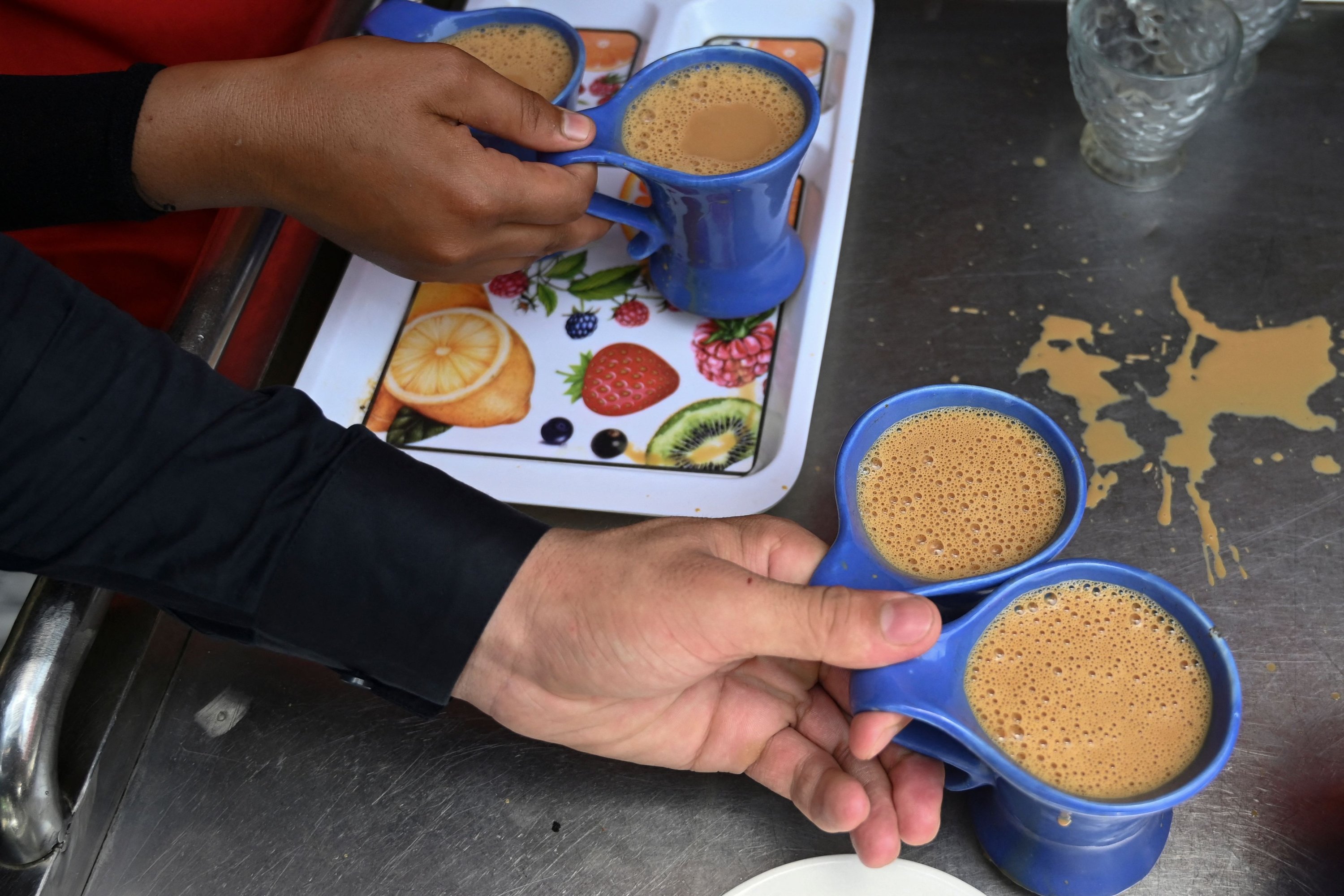 Para pelayan bersiap untuk menyajikan cangkir teh kepada pelanggan di sebuah restoran di Islamabad, Pakistan, 15 Juni 2022. (AFP Photo)