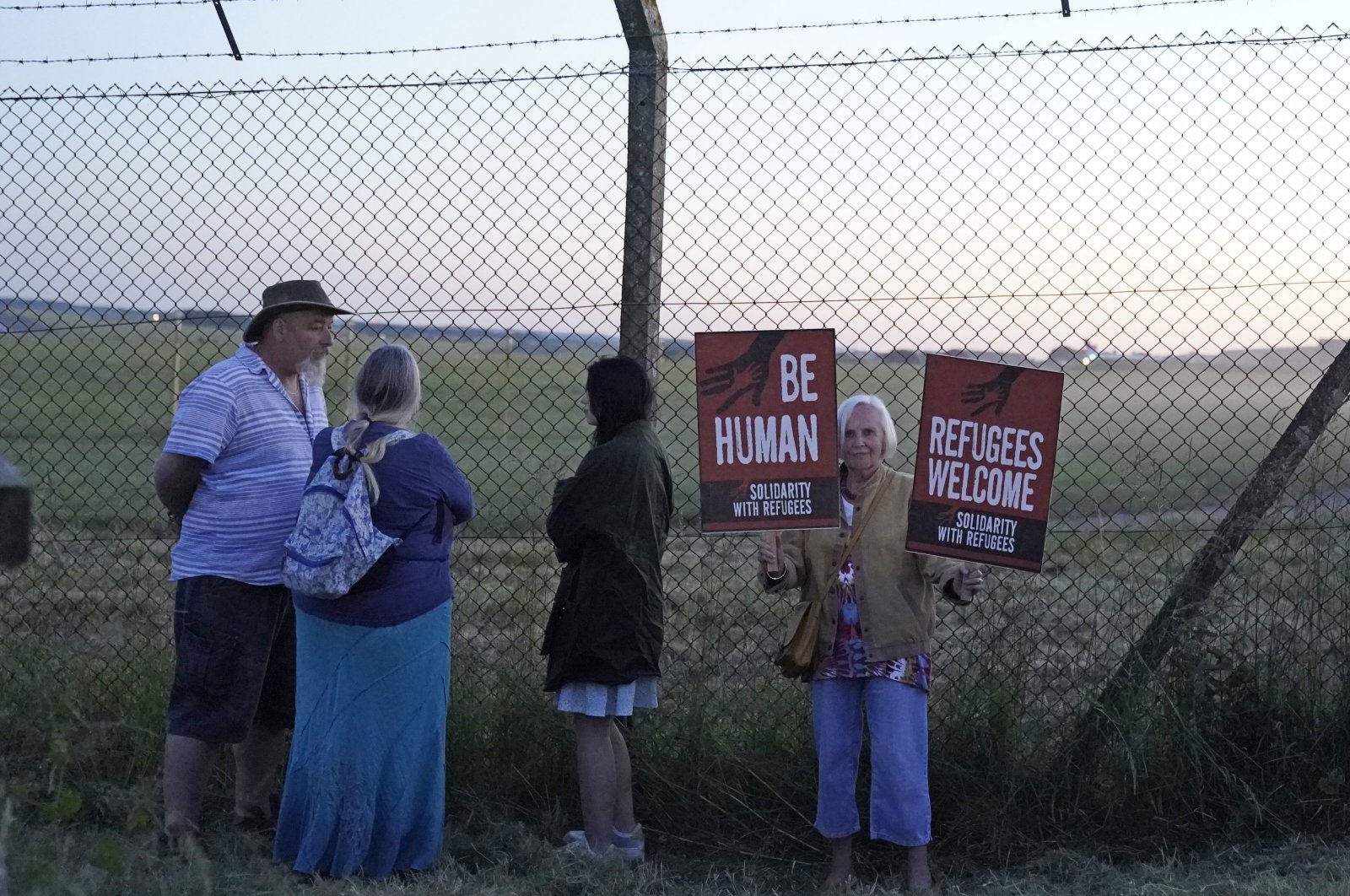 Protesters gather at the perimeter of Boscombe Down air base in Amesbury where the aircraft believed to be the plane set to take asylum-seekers to Rwanda is located, U.K., June 14, 2022. (PA via AP)