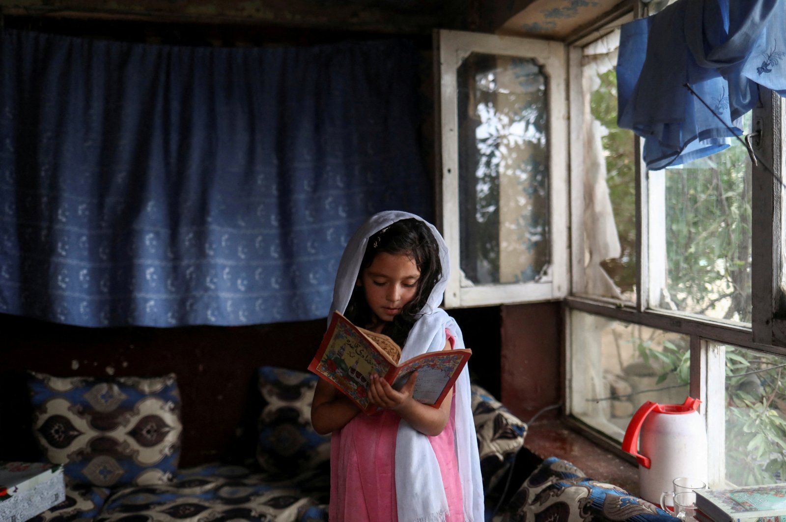 An Afghan girl reads a book inside her home in Kabul, Afghanistan, June 13, 2022. (Reuters Photo)