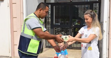 A woman hands over used cooking oil to a municipality worker in exchange of a free gift as part of a campaign, in Bursa, northwestern Turkey, Jun. 14, 2022. (İHA PHOTO) 
