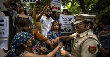 A Delhi police officer snatches placards from student activists during a protest demonstration against a new short-term government recruitment scheme for the military, New Delhi, India, June 17, 2022. (AP Photo)