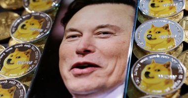 A photo of Elon Musk is displayed on a smartphone placed on representations of cryptocurrency dogecoin in this illustration taken June 16, 2022. (Reuters Photo)