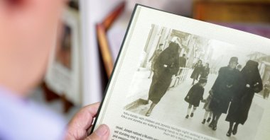 Eli Tauber shows a picture in a book of Rifka Kabiljo and Zeineba Hardaga walking on a street in Sarajevo in 1941, in Sarajevo, Bosnia-Herzegovina, June 13, 2022. (REUTERS)