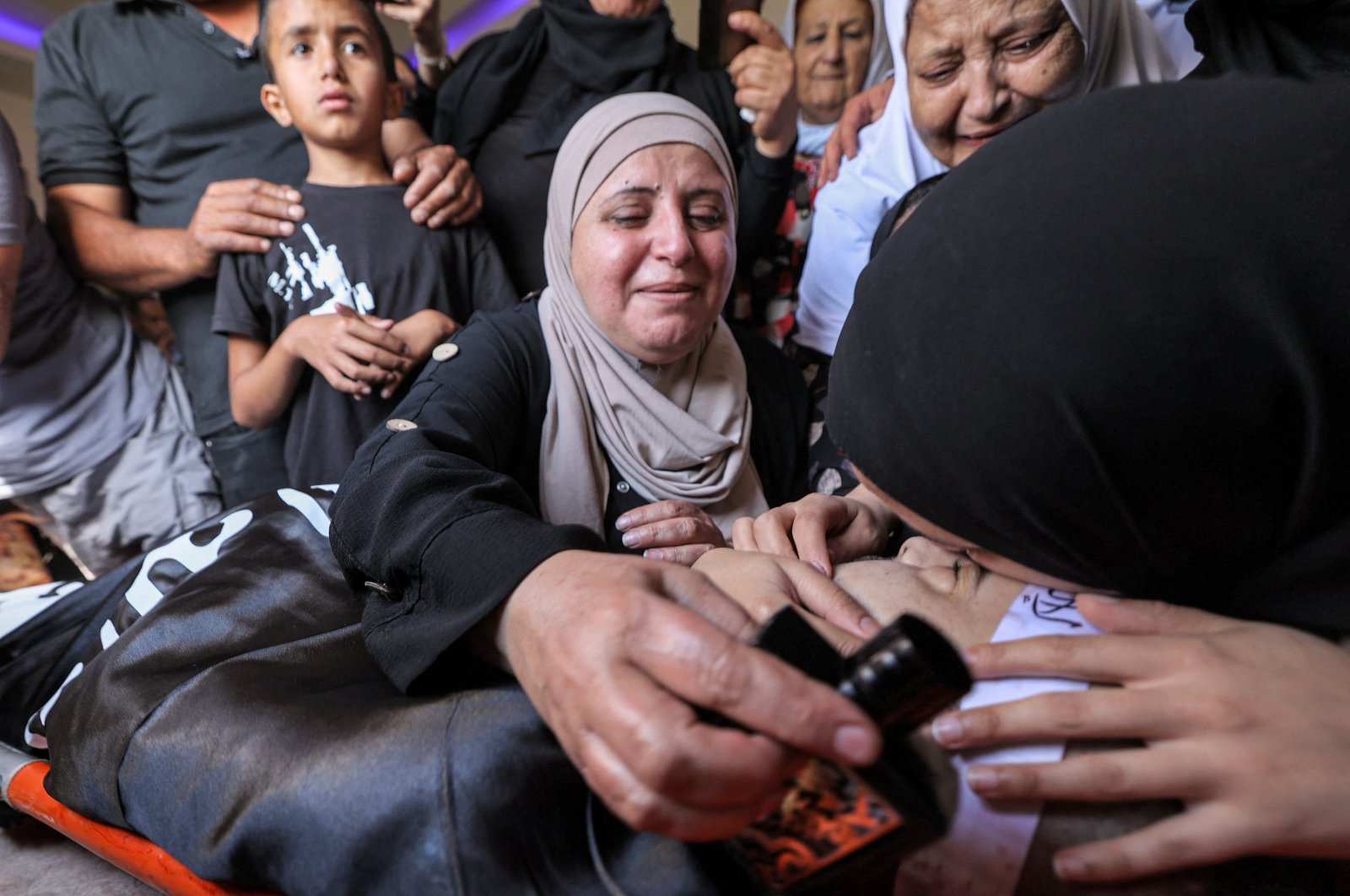 The mother (top) and sisters (bottom) of Palestinian Baraa Lahlouh, 24, one of three Palestinians killed during an operation by Israeli forces in Jenin, react to his body as it arrives at their home in the Jenin camp, West Bank, the occupied Palestine, June 17, 2022. (AFP Photo)