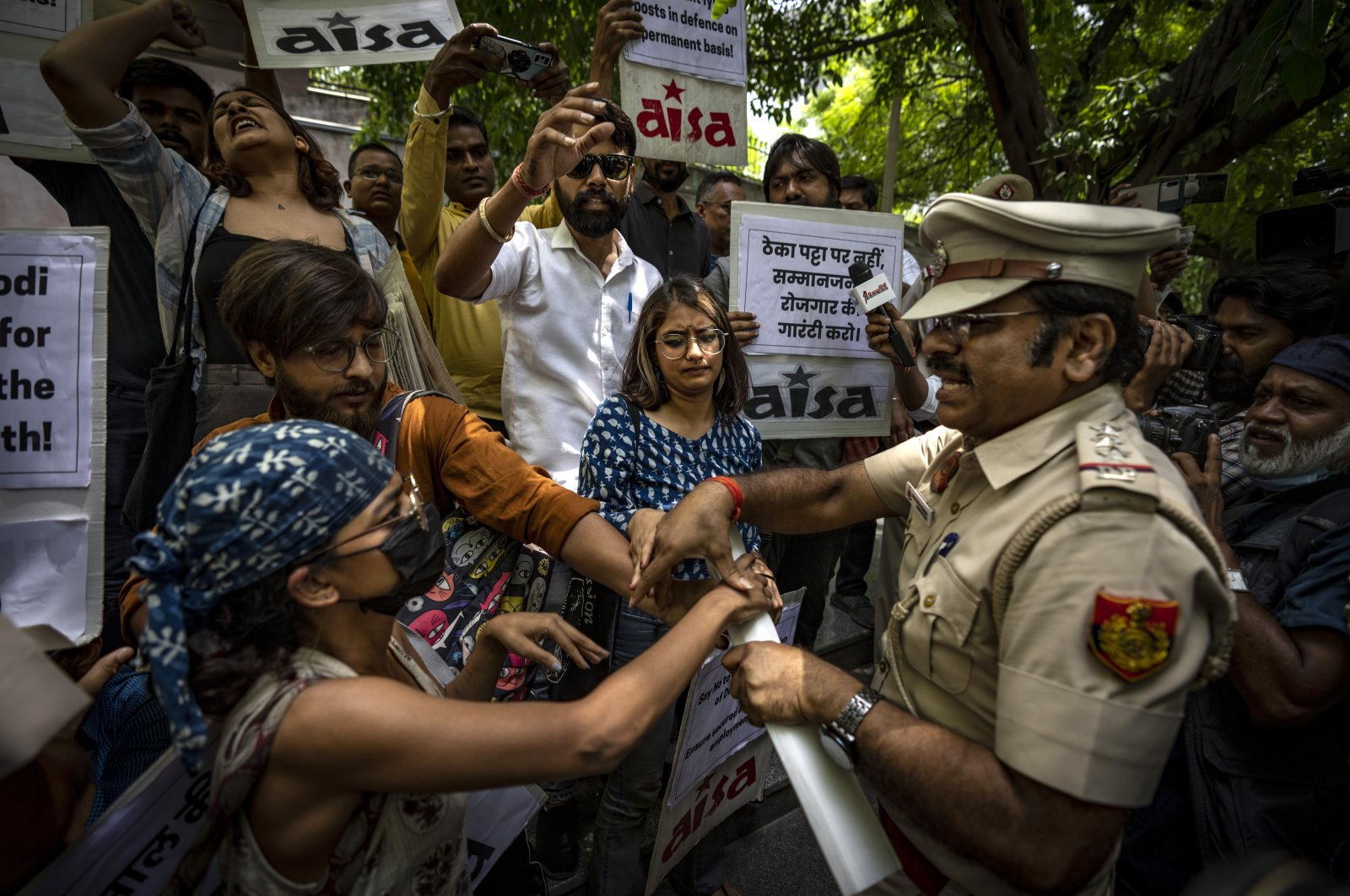 A Delhi police officer snatches placards from student activists during a protest demonstration against a new short-term government recruitment scheme for the military, New Delhi, India, June 17, 2022. (AP Photo)