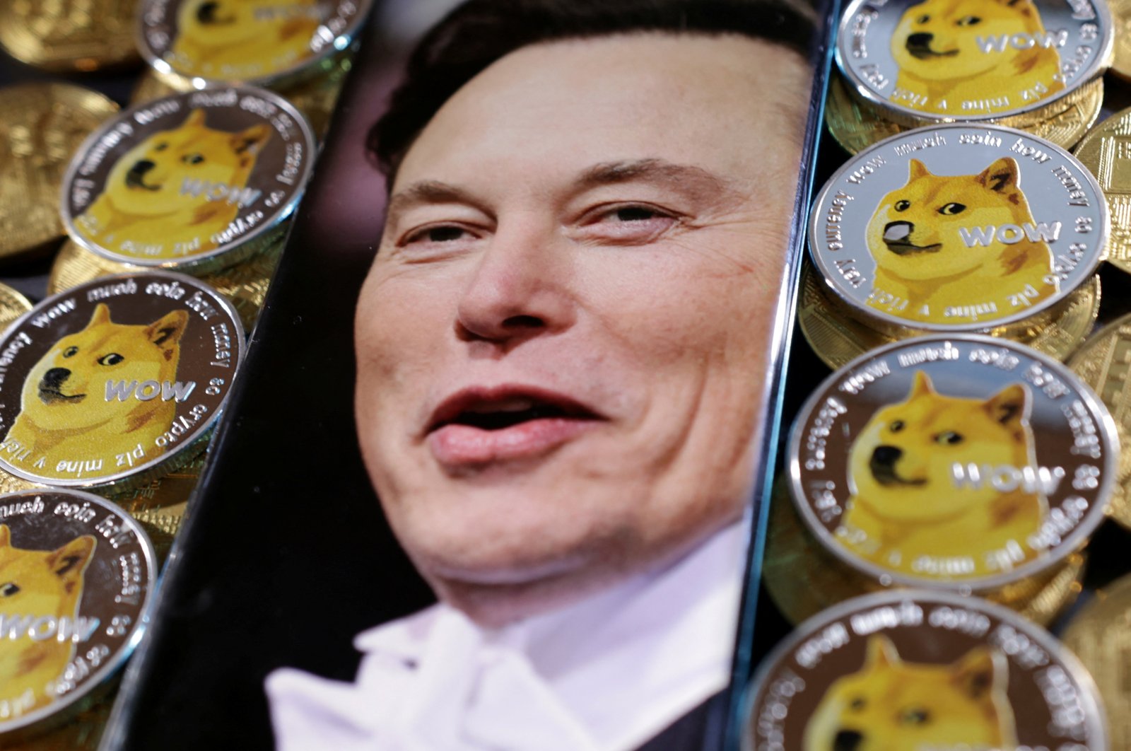 A photo of Elon Musk is displayed on a smartphone placed on representations of cryptocurrency dogecoin in this illustration taken June 16, 2022. (Reuters Photo)