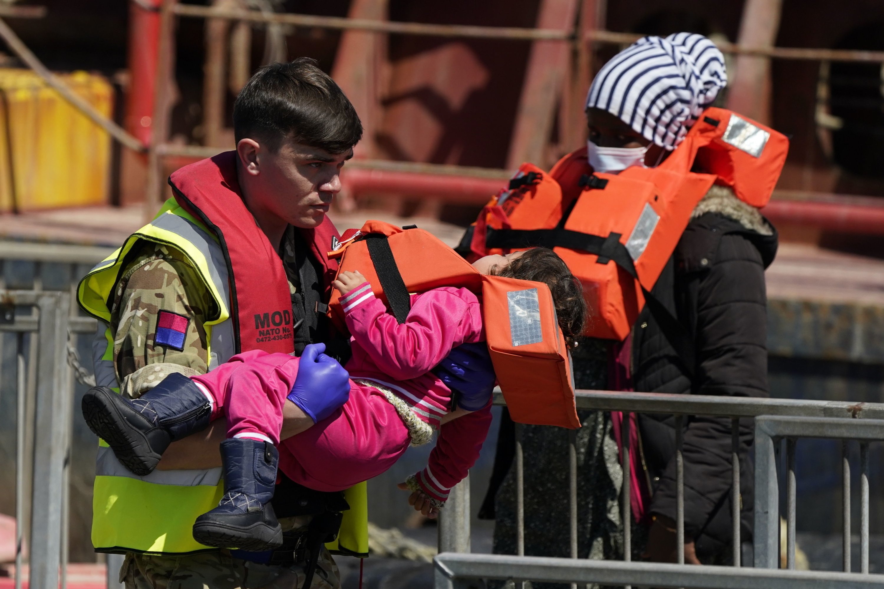 Seorang tentara menggendong seorang anak dari sekelompok orang yang diduga migran dibawa ke Dover, Inggris, oleh Border Force, menyusul insiden perahu kecil di Selat, 14 Juni 2022. (AP Photo)