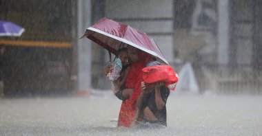 A woman with children wades along a flooded street during a monsoon rainfall in Sylhet, Bangladesh, June 18, 2022. (AFP Photo)