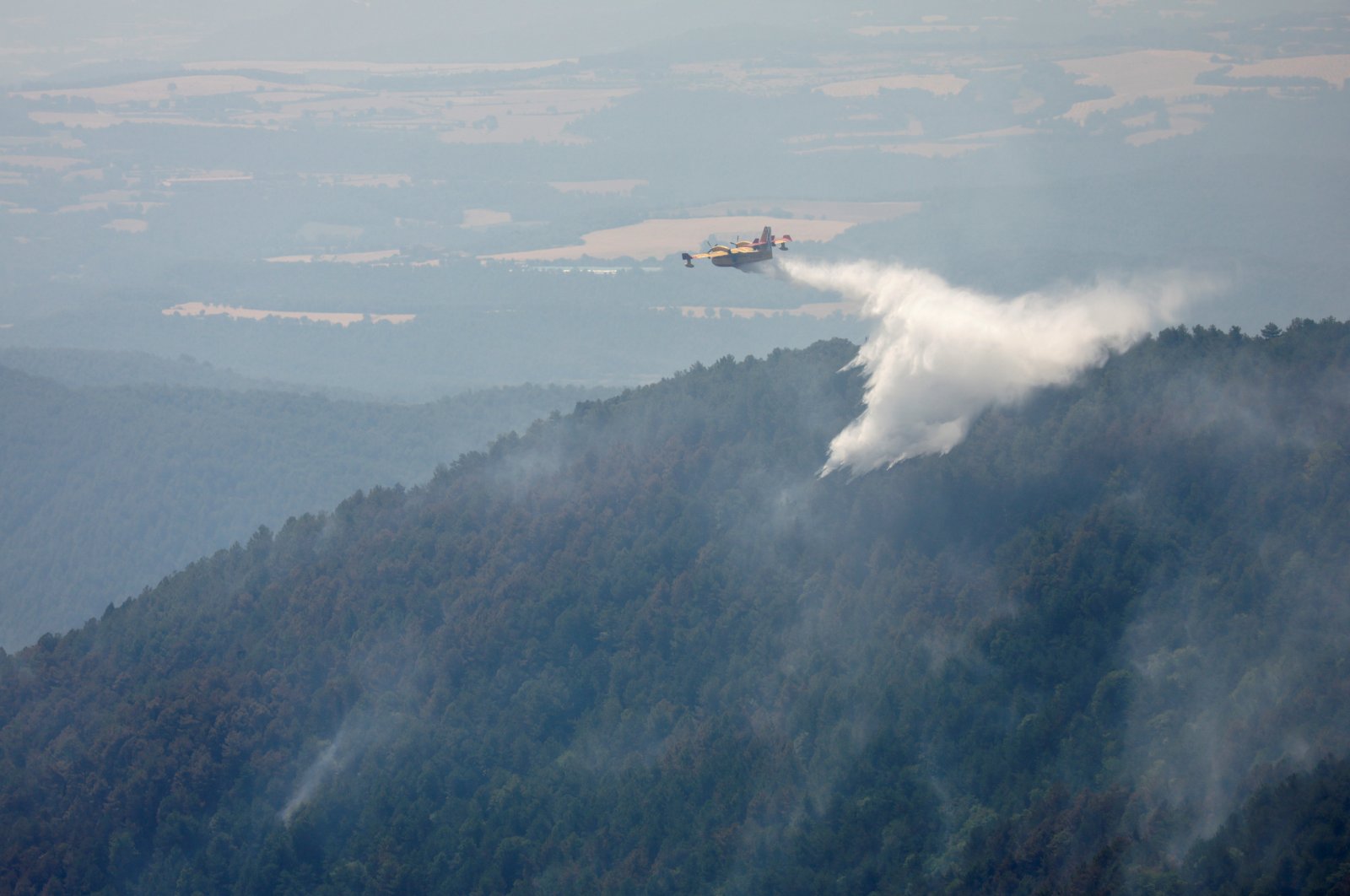 A plane drops water onto a wildfire near Lladurs, Spain, June 17, 2022. (Reuters Photo)